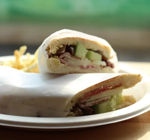 A halved wrap sandwich with cucumber on a white plate