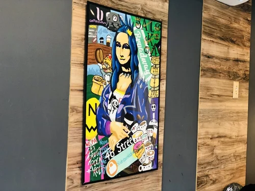A framed street-art portrait on a wood wall