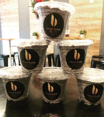 A pyramid of lidded cookie-crumb dessert cups printed with the Sweet Habit b mark