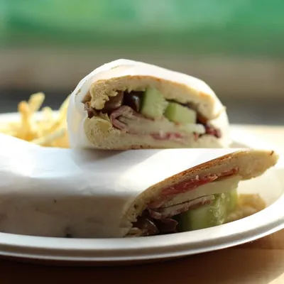A halved wrap sandwich with cucumber on a white plate