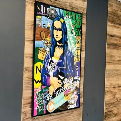 A framed street-art portrait on a wood wall