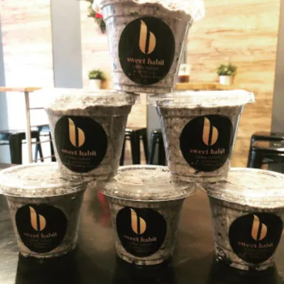 A pyramid of lidded cookie-crumb dessert cups printed with the Sweet Habit b mark